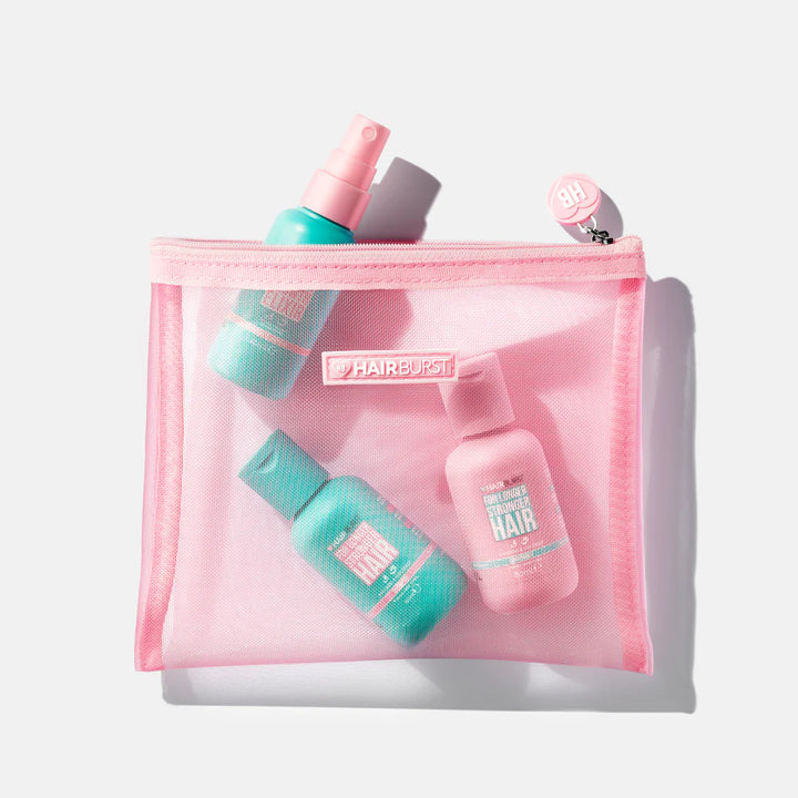 Pink mesh wash bag with Hairburst branding. Filled with Hairburst mini shampoo & onditioner and mini elixir spray