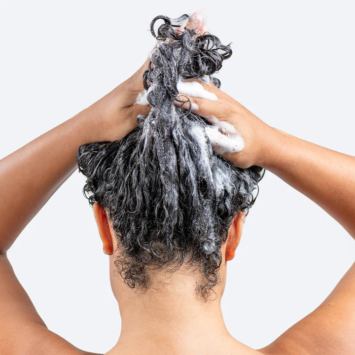 Person washing hair with hairburst shampoo & conditioner for curly and wavy hair